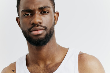 Confident african american man in a white tank top looking directly at the camera in a relaxed,...