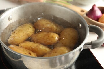 Boiling potatoes in metal pot on stove, closeup