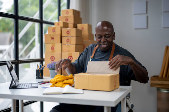 A man is sitting at a desk with a laptop and a box in front of him