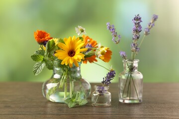 Different flowers in glass bottles on wooden table