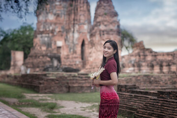 Fototapeta premium Portrait of beautiful woman wearing a Thai dress Visit Phra Nakhon Si Ayutthaya Historical Park. Asian woman wearing Thai Traditional on the World Heritage Historical Park in Ayutthaya ,Thailand.