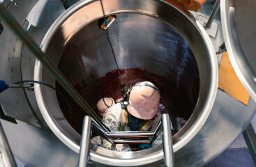 Top view male climbs up the stairs into the tank stainless chemical area inside confined