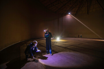 Male two worker inspection scan tank of rust thickness bottom plate area tank inside confined