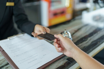 Hotel receptionist in uniforms Concierge giving the key doing check-in at the hotel desk in lobby...