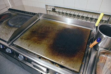 Stainless steel professional kitchen restaurant griddle hot heat plane silver surface. Griddle in professional kitchen in restaurant.