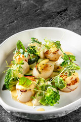 Seared scallops with green vegetables in a white bowl