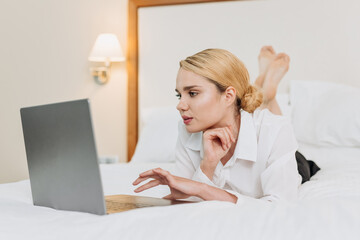 Blonde business woman works in the evening in a hotel room during a business trip. Work-life balance, leisure and corporate travel.