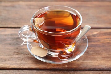 Brewing aromatic tea. Cup with teabag and spoon on wooden table