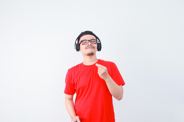 photo of a happy, attractive young Indonesian man wearing earphones, celebrating Indonesian independence