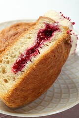 Round croissant with jam on table, closeup. Tasty puff pastry