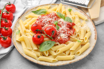 Tasty pasta with tomato sauce, cheese and basil on grey table