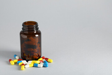Antibiotic pills and bottle on grey background, space for text. Medicinal treatment