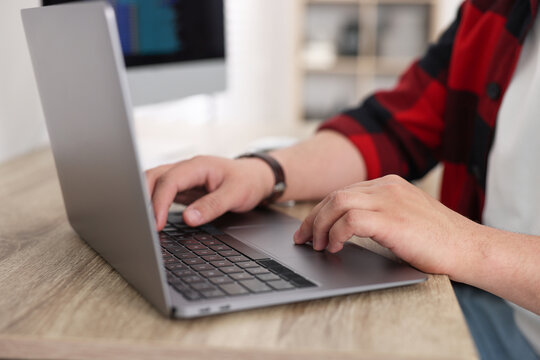 Programmer working with laptop at desk in office, closeup