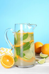 Freshly made lemonade with mint in jug on white wooden table against light blue background