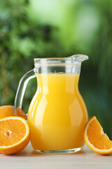 Tasty orange juice in glass jug and fresh fruits on white wooden table outdoors