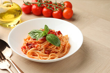 Delicious pasta with tomato sauce and basil in bowl on wooden table