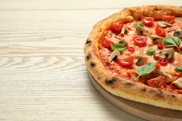 Delicious pizza with tomatoes, mushrooms and basil on wooden table, closeup. Space for text