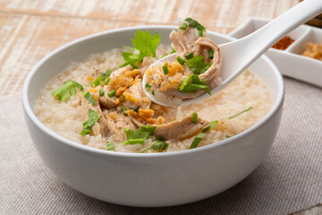 Close up Chicken Porridge in spoon,rice soup with Shredded chicken breast in white bowl.Asian breakfast style