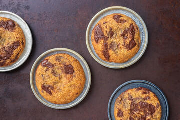 Homemade chocolate chip cookies in ceramic plates on rustic background.