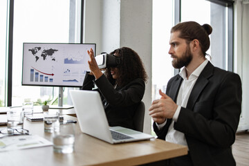 Colleagues exploring virtual reality technology during business meeting in modern office setting. Professional presentation with graphs and charts on screen.