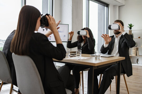 Business team using virtual reality headsets during office meeting, exploring immersive tech. Engaged colleagues in workspace, embracing innovation and technology for collaboration and visualization.