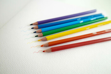 Pencils in rainbow colors on a white sheet