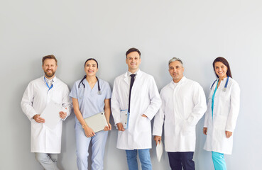 Portrait of a group of happy doctors in uniform on a gray background. Friendly medical staff at the...