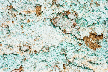 Close up of a weathered and peeling turquoise painted wall with exposed brown patches, texture, background.