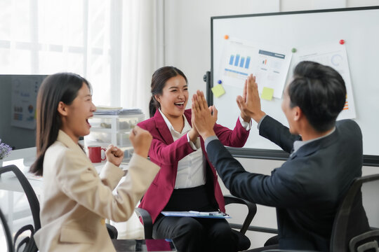 Business team celebrating success with high five in modern office. Diverse colleagues sharing a moment of achievement and joy.