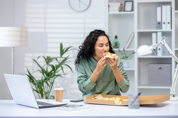 A woman eating pizza at her desk during a work break in a modern office setting. The scene captures...