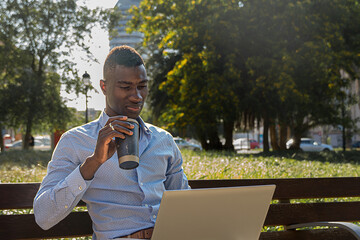 African American businessman drinking coffee while working with laptop outdoors