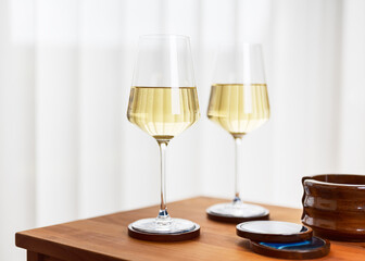 Romantic party with two glasses of delicious white wine in a cozy living room with a Scandinavian style interior. Copy space.