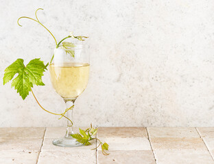 Minimal aesthetic still life with white wine. Glass of white wine with grape leafs on a vintage...