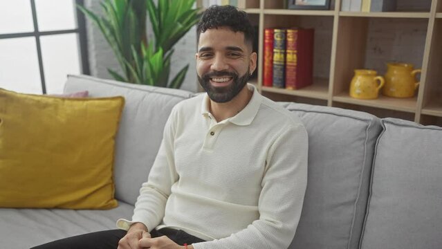 Happy young hispanic man, capturing a lucky moment at home with a charming smile and cool confidence