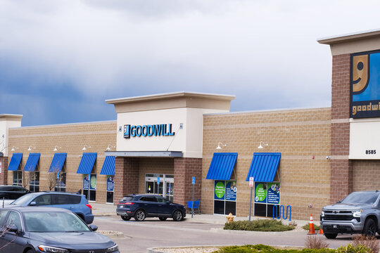 Goodwill thrift store entrance with company logo brand name logo sign and parking lot with parked cars.