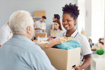 Poor people get welfare assistance. Helpful friendly smiling African American volunteer girl gives...