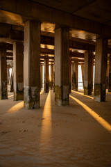 sunrise or sunset underneath the pier by the ocean