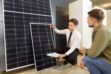 Solar energy consultant engages in a meeting with a client in the shop, showing sources of...