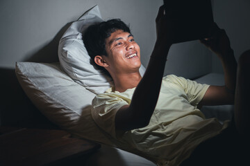 Young man using tablet in bed at night