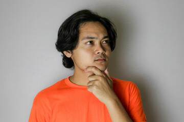 Portrait of an Asian Indonesian young man wearing a orange shirt with a random expression when photographed with an isolated white background