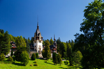 The Peles castle in the town of Sinaia, Transylvania, Carpathian Mountains, Romania, Summer time, bright sunny day with dark blue sky. The Peles castle is the most impressive castle in Romania.