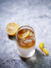 Cold espresso tonic with a slice of lemon on a stone table. Refreshing summer coffee drink