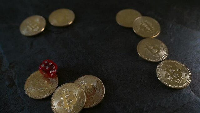 Slow motion dice rolling past gold bitcoins