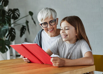 grandchild family child grandparent grandmother book reading elderly granddaughter girl  happy...