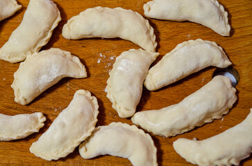 Raw dumplings on a cutting board. brown background.