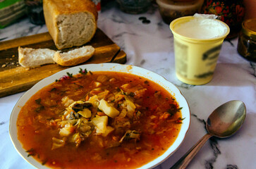 Russian cabbage vegetable soup in the plate, sour cream and bread. Tasty food