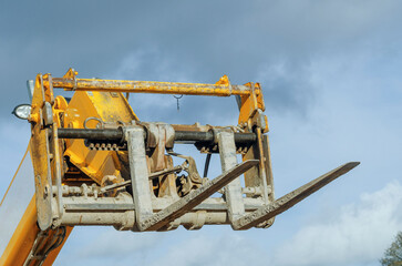 Yellow Forklift Attachment Detail Against Cloudy Sky