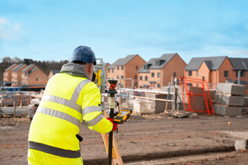 Construction Worker Using Surveying Equipment at New Housing Development Site