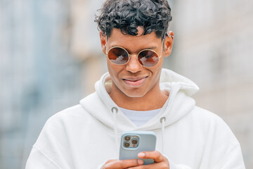 young latin man with sunglasses looking at mobile phone