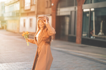 Obraz premium Happy Woman Walking With Flowers in Downtown City on Sunny Day